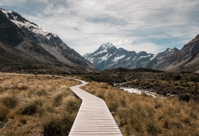 Brown wooden dock, mountains near streams and glaciers in the mountains
